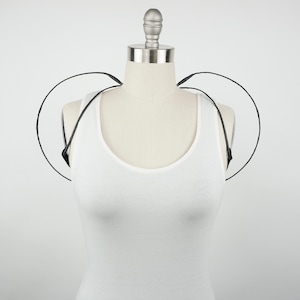 May include: A black wire shoulder piece with two circular hoops. The shoulder piece is worn on a white tank top mannequin.