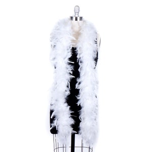 May include: A white feather boa draped over a black dress form. The boa is long and fluffy, and it would be perfect for a costume or party.