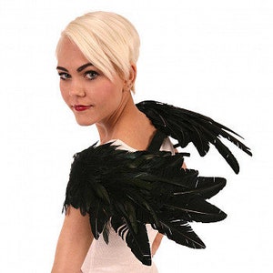 Puede incluir: Accesorio de disfraz de alas de plumas negras. Las alas est&aacute;n sujetas a una correa que se coloca sobre los hombros.