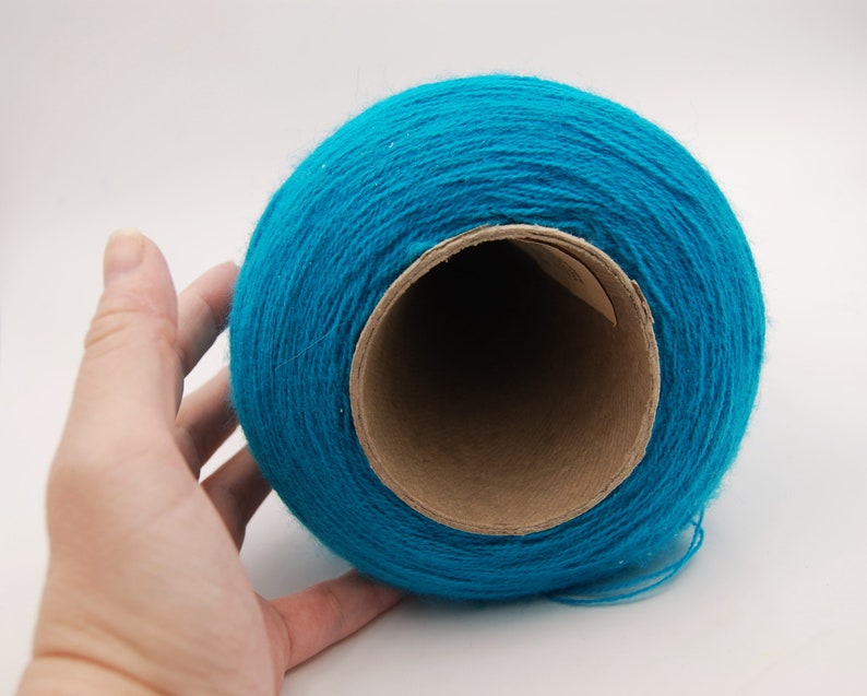 Puede incluir: Un rollo de hilo turquesa brillante enrollado alrededor de un tubo de cart&oacute;n.
