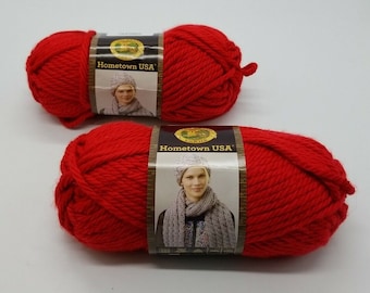 Puede incluir: Dos ovillos de hilo rojo etiquetados "Hometown USA" de Lion Brand Yarn.