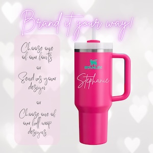 Op de afbeelding: Een felroze Stanley-beker met een witte deksel en handvat. De beker heeft de naam "Stephanie" in cursief schrift. De afbeelding bevat ook tekst: "Brand it your way!" en opties voor personalisatie.