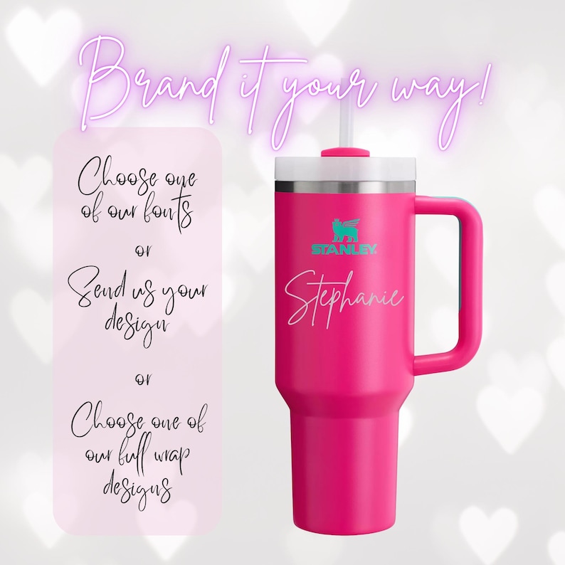 Op de afbeelding: Een felroze Stanley-beker met een witte deksel en handvat. De beker heeft de naam "Stephanie" in cursief schrift. De afbeelding bevat ook tekst: "Brand it your way!" en opties voor personalisatie.