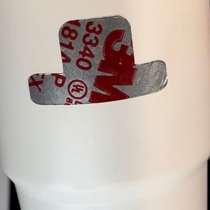May include: White insulated tumbler with a silver rim. A silver and red 3M sticker in the shape of a hat is affixed to the tumbler. The sticker has the numbers "3340" and "181A" printed on it.