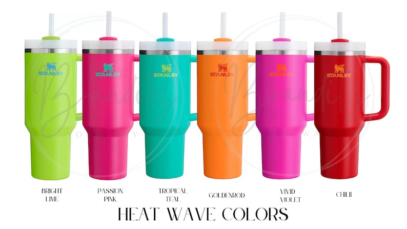 Op de afbeelding: Een verzameling van zes Stanley-bekers in levendige kleuren: fel lime, passion pink, tropisch teal, goudgeel, fel violet en chili. Elke beker heeft een handvat, een deksel en een rietje. De tekst "HEAT WAVE COLORS" staat eronder.