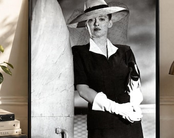 May include: A black and white framed wall art print featuring a portrait of a person wearing a wide-brimmed hat with a veil, a dark jacket with a white collar, and white gloves. The person stands next to a large, smooth, light-colored pillar.