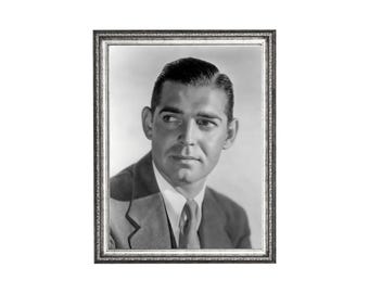 May include: Black and white framed portrait of a man in a suit and tie. The portrait is in a silver-colored frame. The man has dark hair and is looking off to the side.