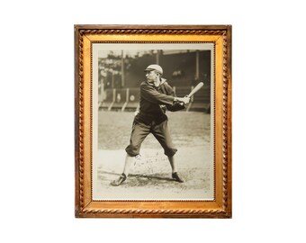 May include: Framed sepia-toned photograph of a baseball player in a batting stance, holding a bat. The image is in a gold-colored wooden frame with a decorative rope-like border. The player is wearing a cap and uniform.