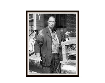 May include: A black and white photograph of a person wearing a dark jacket, a patterned button-down shirt, and a bow tie. The person is holding a pocket watch on a chain in one hand and standing in front of a brick building with a bicycle nearby.