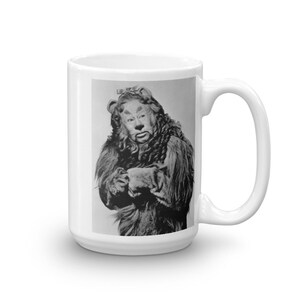 May include: A black and white photo of the Cowardly Lion from the Wizard of Oz. The lion is wearing a lion costume with a mane and a tail. The lion is looking at the camera with a serious expression.