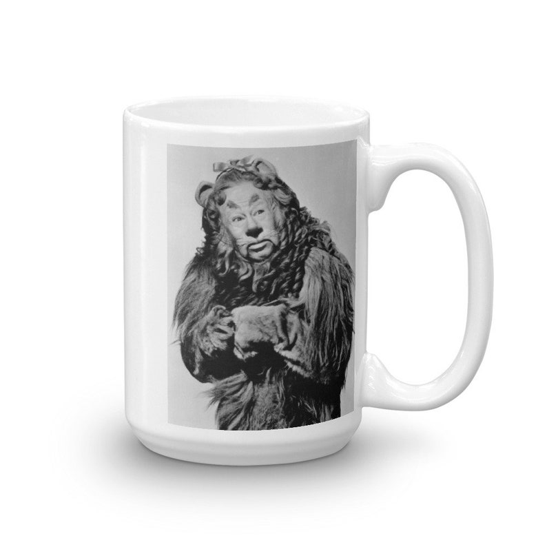 May include: A black and white photo of the Cowardly Lion from the Wizard of Oz. The lion is wearing a lion costume with a mane and a tail. The lion is looking at the camera with a serious expression.