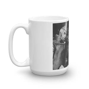 Puede incluir: Una taza de cer&aacute;mica blanca con una imagen en blanco y negro del Hombre de Hojalata de El Mago de Oz. El Hombre de Hojalata lleva un sombrero plateado y un traje plateado. Est&aacute; mirando hacia la derecha.