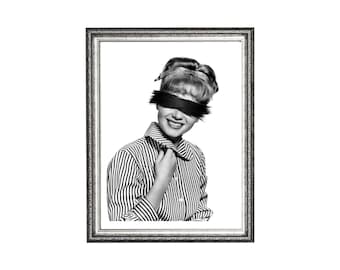 May include: Black and white framed print featuring a vintage photograph of a woman with a black bar obscuring her eyes. She wears a striped button-down shirt and smiles. The frame is silver with ornate detailing.