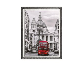 May include: A black and white photograph of a red double-decker bus driving past St. Paul's Cathedral in London, England.