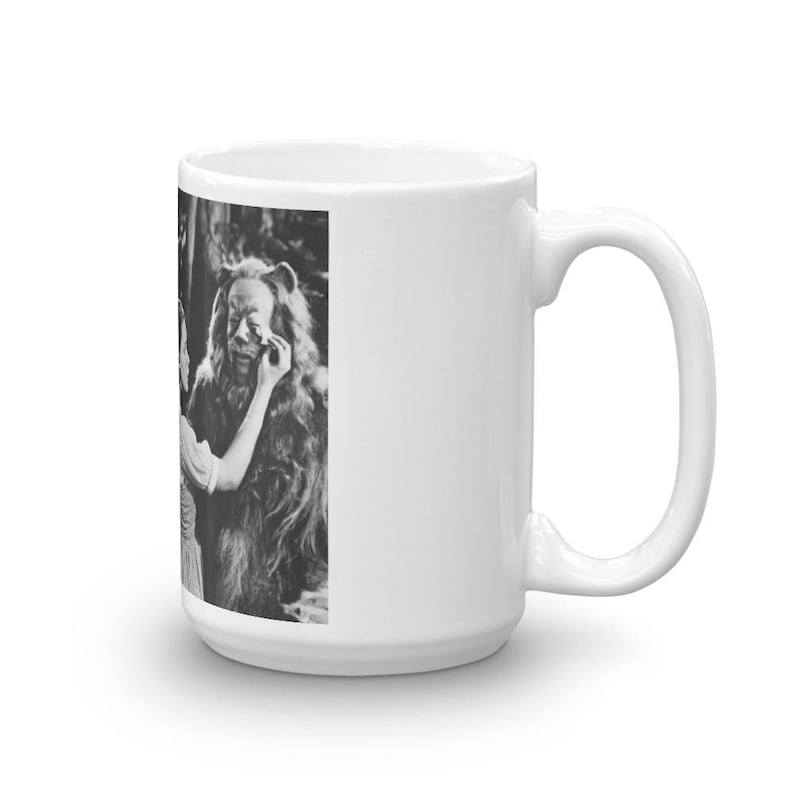 Puede incluir: Una taza de cer&aacute;mica blanca con una imagen en blanco y negro de una mujer maquillando a un le&oacute;n. La imagen es de la pel&iacute;cula El mago de Oz.
