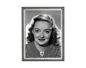 May include: Black and white framed portrait of a woman with curly hair, wearing a polka dot top and a brooch. The portrait is in a silver-colored frame, and the woman is smiling.