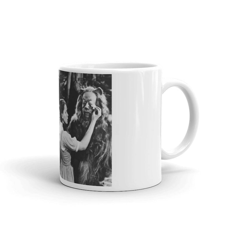 Puede incluir: Una foto en blanco y negro de una mujer maquillando a un le&oacute;n. La mujer lleva un vestido y el le&oacute;n lleva un disfraz. La foto est&aacute; impresa en una taza de cer&aacute;mica blanca.