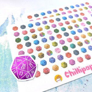 May include: A sheet of colourful watercolour d20 dice stickers. The stickers are arranged in a grid pattern and feature a variety of colours and designs. There is a larger sticker of a single d20 die in the bottom left corner. The sticker is purple and features white numbers.
