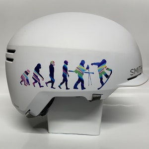 May include: White ski helmet with a colorful graphic of a snowboarder and a series of stick figures representing the evolution of man. The helmet has the word "SMITH" printed on the side.