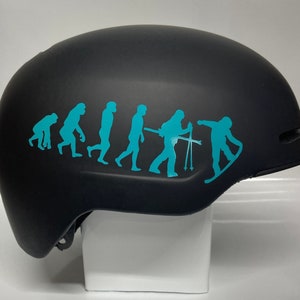 May include: A black ski helmet with a turquoise blue evolution of man sticker. The sticker shows a series of stick figures progressing from a hunched-over ape to a modern human holding ski poles and standing on a snowboard.