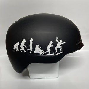 May include: Black helmet with a white silhouette of the evolution of transportation, starting with a monkey and ending with a person skateboarding.
