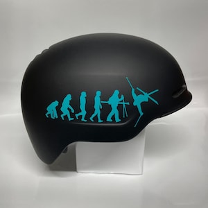 May include: Black ski helmet with a turquoise evolution of man sticker featuring a skier doing a trick at the end of the line.