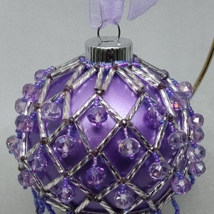 May include: Purple Christmas ornament with a silver beaded cage and purple beads hanging from the bottom.