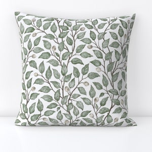 May include: A white throw pillow with a green leafy pattern. The pillow features a repeating pattern of leaves and small white berries.
