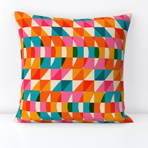 May include: A colorful geometric pattern pillow cover with a repeating design of orange, pink, blue, green, and white squares and curved shapes.