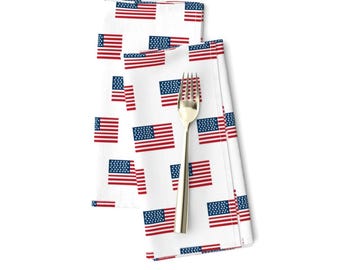 Op de afbeelding: Twee witte stoffen servetten met een herhalend patroon van kleine Amerikaanse vlaggen. De vlaggen zijn rood, wit en blauw.