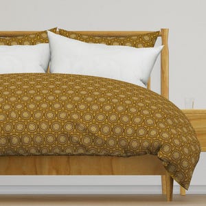 May include: A gold and brown patterned duvet cover with a white pillow on a wooden bed frame.