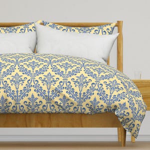 May include: A yellow and blue patterned duvet cover with a damask design. The duvet cover is on a bed with a wooden headboard.