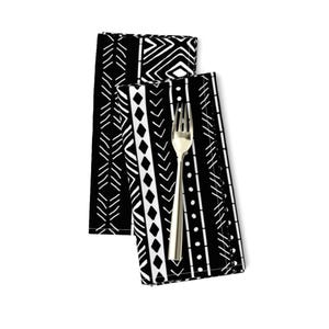 May include: Two black and white patterned cloth napkins with a geometric design. The napkins are folded and stacked on top of each other.