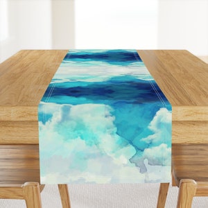 Könnte beinhalten: Ein blauer und weißer Aquarell-Tischläufer mit einem Design aus Wolken und Himmel. Der Läufer ist aus Stoff und hat einen genähten Rand.