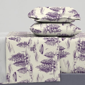 May include: A set of bedding with a cream background and a purple print of trees and flying saucers. The bedding includes a flat sheet, fitted sheet, and two pillowcases.