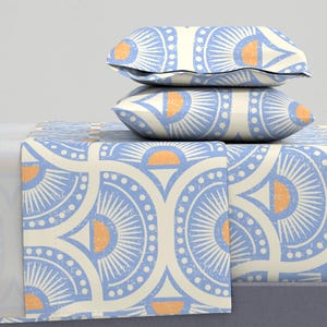 May include: A blue and white patterned bedding set with a geometric design featuring orange accents. The set includes a flat sheet, fitted sheet, and two pillowcases.