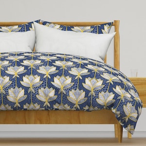 May include: A navy blue duvet cover with a white and yellow floral pattern. The duvet cover is on a bed with a wooden headboard and frame.