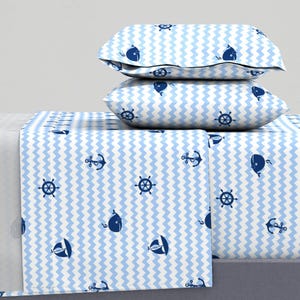 May include: A blue and white striped bedding set with a nautical theme. The set includes a flat sheet, fitted sheet, and two pillowcases. The pattern features anchors, whales, and steering wheels.