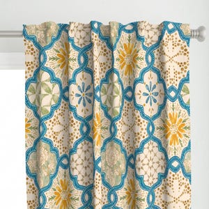 May include: Cream-colored curtain with a repeating pattern of blue, yellow, and green floral and geometric designs. The design includes a trellis-like structure with dotted accents, creating a decorative window treatment.
