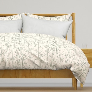 May include: A white duvet cover with a light green bamboo print. The duvet cover is on a wooden bed frame with two white pillows.