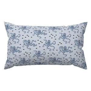 May include: A light blue pillow with a pattern of blue octopuses and black fish swimming on a white background.
