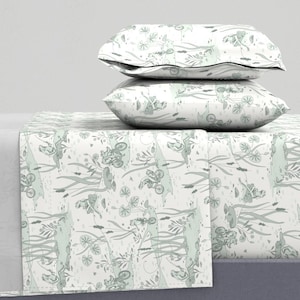 Peut inclure: Ensemble de literie avec un motif fantaisiste de vélos, de plantes et de personnages dans des tons de vert et de gris sur fond blanc. L'ensemble comprend deux taies d'oreiller et un drap-housse, créant un ensemble de chambre à coucher cohérent et décoratif.