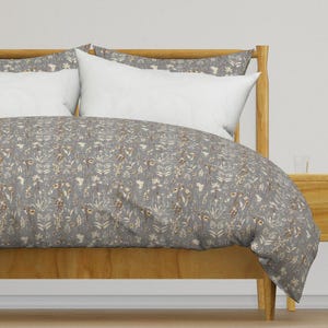 May include: A grey duvet cover with a white and brown floral pattern. The duvet cover is on a wooden bed frame with white pillows.