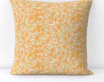 May include: A square cushion with a floral pattern in shades of orange and yellow on a cream background.