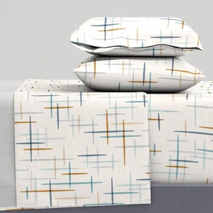 May include: A white bedding set with a geometric pattern of blue, brown, and teal lines. The set includes a fitted sheet, flat sheet, and two pillowcases.