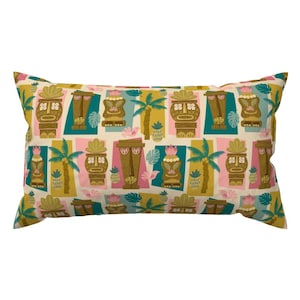 May include: A rectangular pillow with a pattern of tiki heads, palm trees, pineapples, and tropical birds in shades of brown, green, pink, and yellow on a cream background.