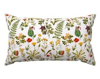 May include: A white pillow with a floral pattern featuring red, yellow, and green flowers. The pillow is rectangular and has a white background.