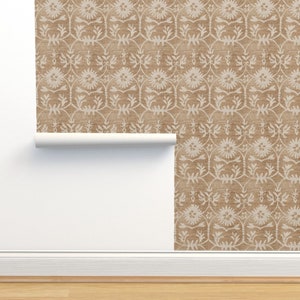 May include: A roll of wallpaper with a brown background and a white floral pattern. The wallpaper is being unrolled to show the pattern.