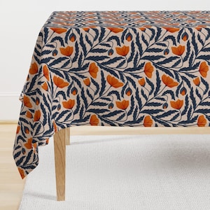Puede incluir: Un mantel beige con un patrón repetido de flores de amapola naranja y enredaderas de hojas azul oscuro.