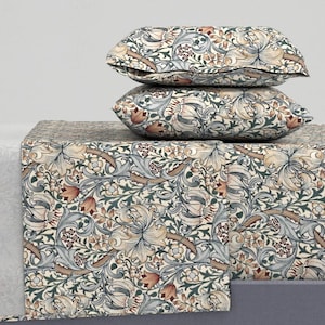 May include: A set of bedding with a floral pattern featuring lilies, leaves, and vines in shades of blue, green, brown, and orange on a cream background.
